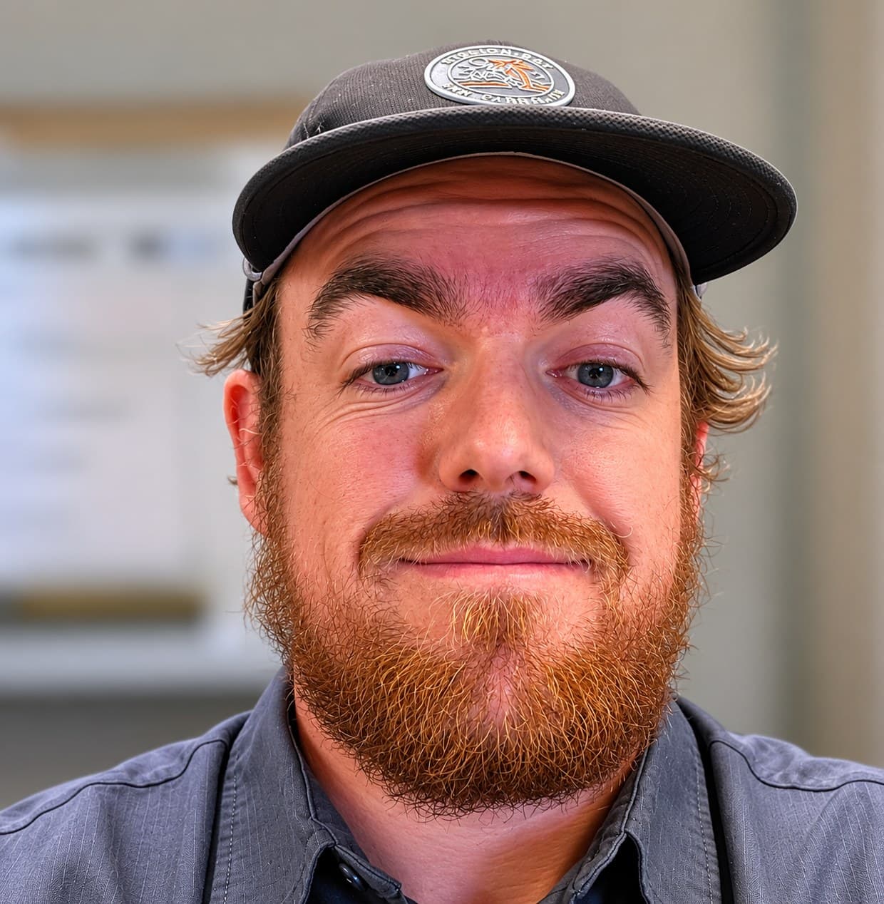 Jay H., bearded, in a work shirt and cap