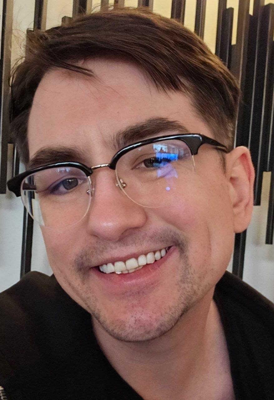 Jordan H., smiling, in front of a vertical-slat background